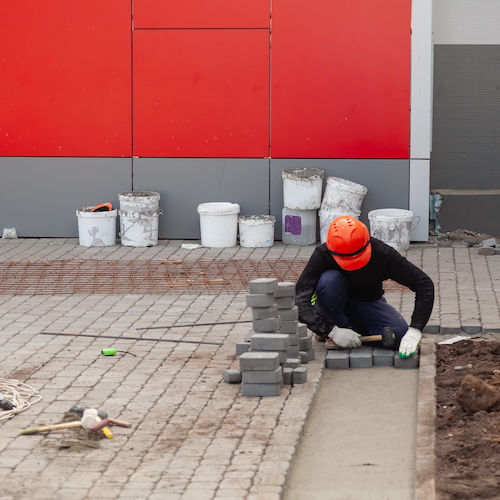 man installing a new paver driveway with brick pavers